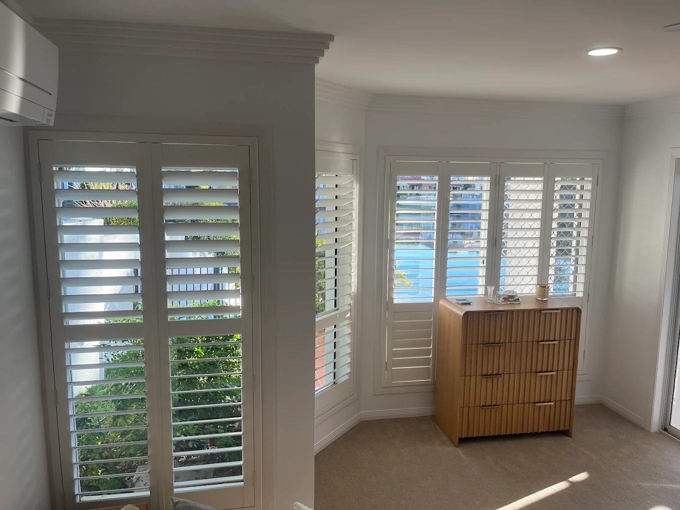 White plantation shutters in a bedroom with timber drawers
